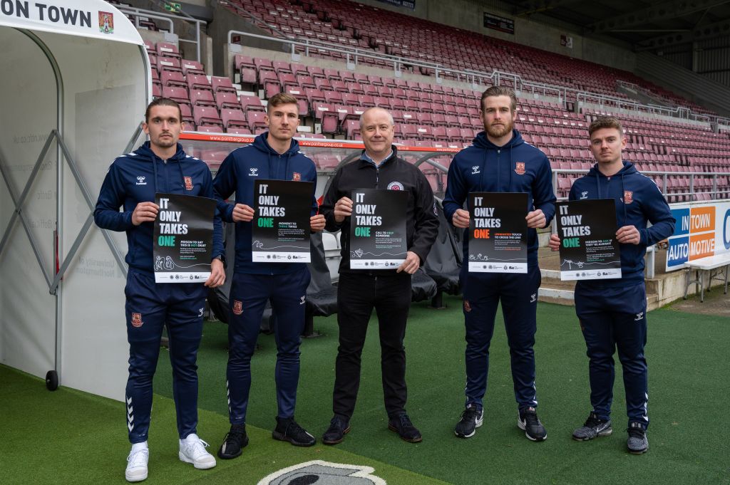 Harvey Lintott, Ben Fox, Stephen Mold, Lee Burge and Sam Hoskins holding It Only Takes One Poster by the tunnel at Sixfields Stadium 